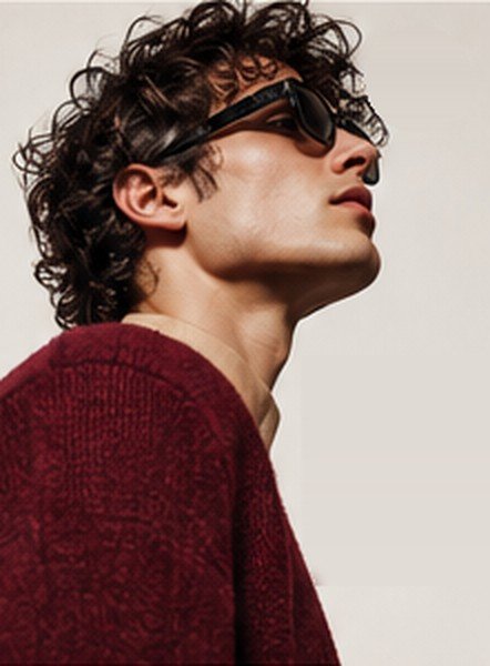 Model with curly hair in sunglasses and a burgundy knit